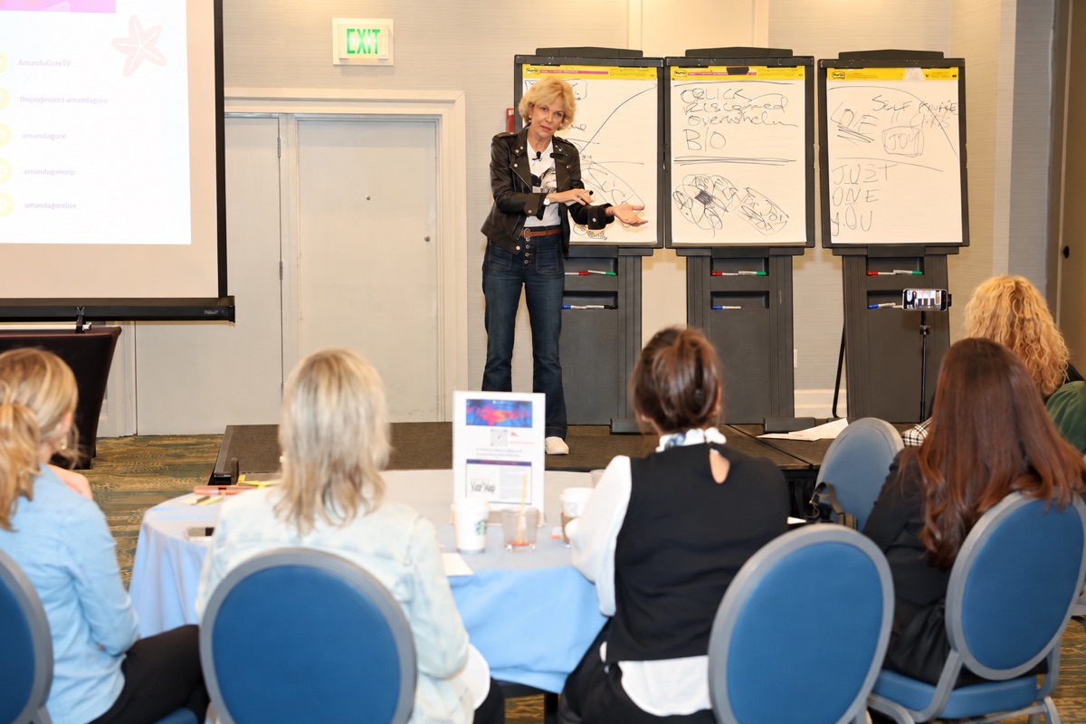 Amanda Gore, leadership speaker, leading a hands-on workshop at three flip charts, with participants at round tables